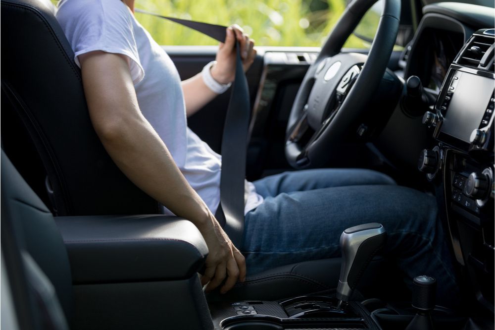 Žena za volantem si zapíná bezpečnostní pás
